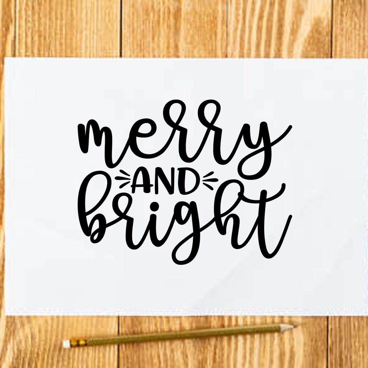 Merry and Bright Christmas rubber stamp design in black script on white paper over a wood background.