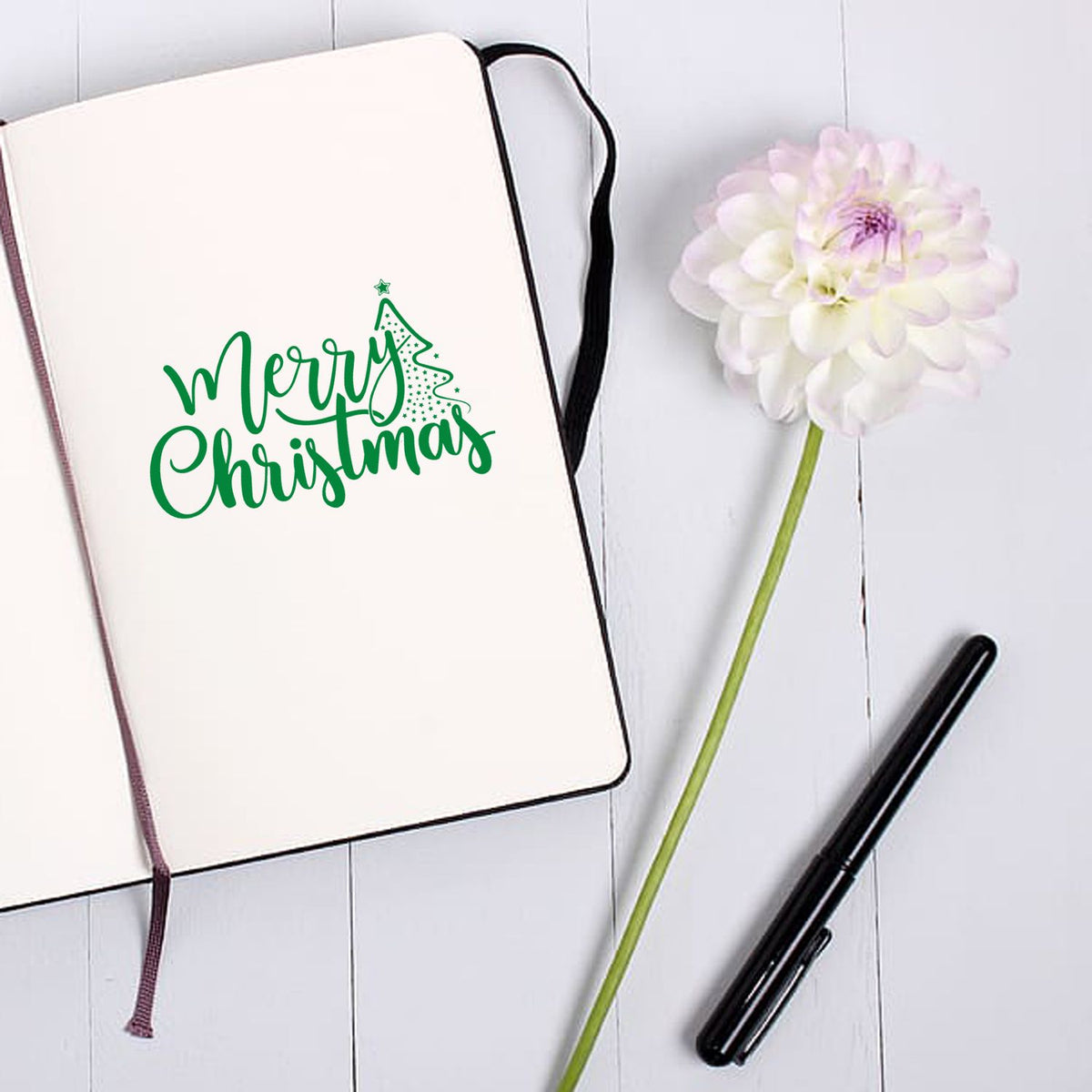 Merry Christmas holiday rubber stamp on notebook, ideal for festive card making, journaling, and gift packaging.