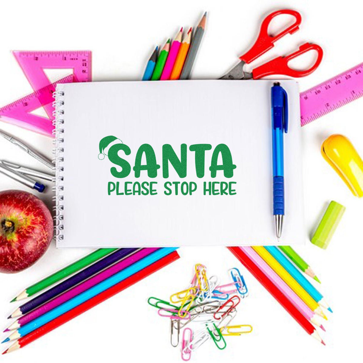 Santa Please Stop Here Christmas rubber stamp design for holiday wish lists, shown on a notebook with school supplies.
