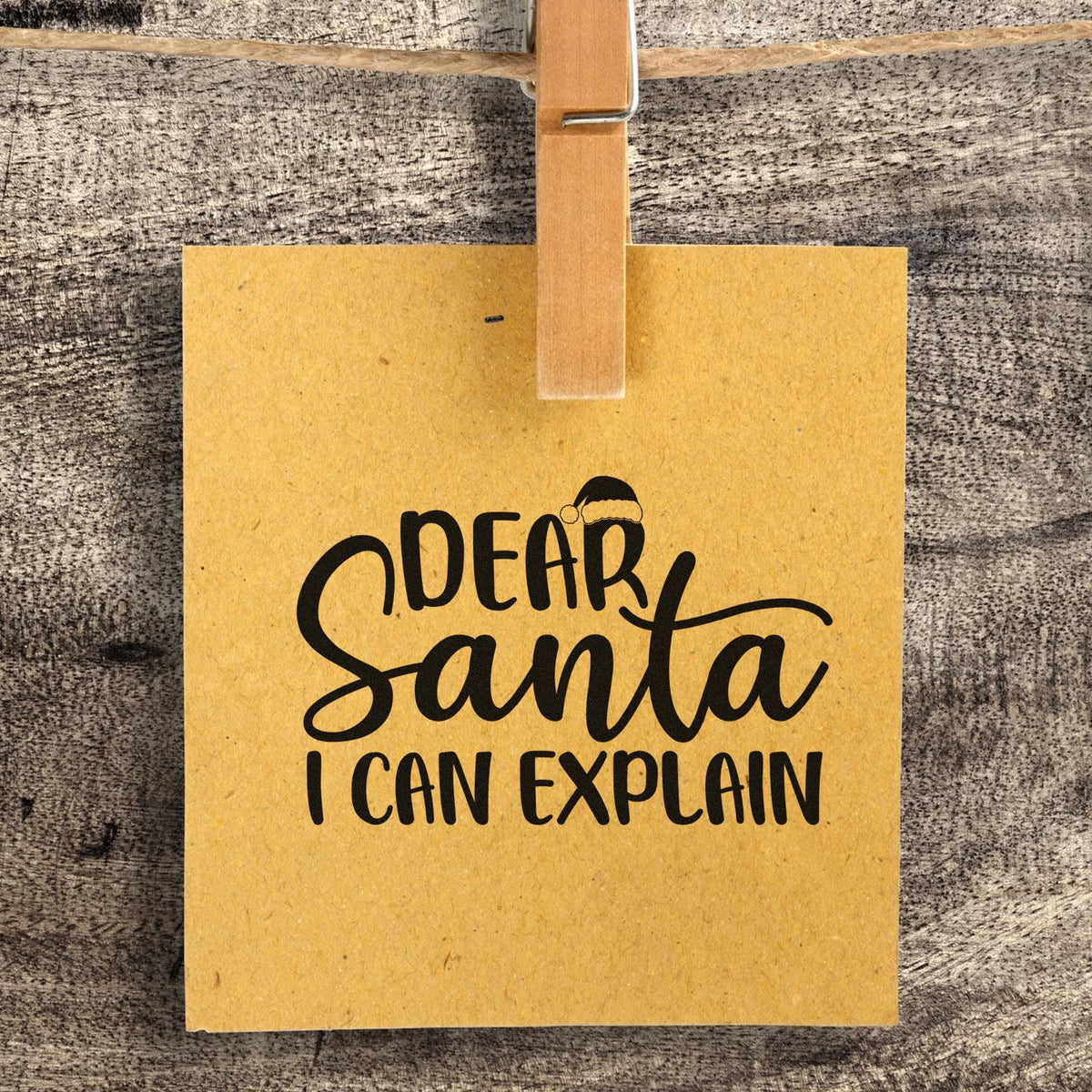 Dear Santa I Can Explain Christmas rubber stamp on kraft paper tag, clipped to rustic wood background.