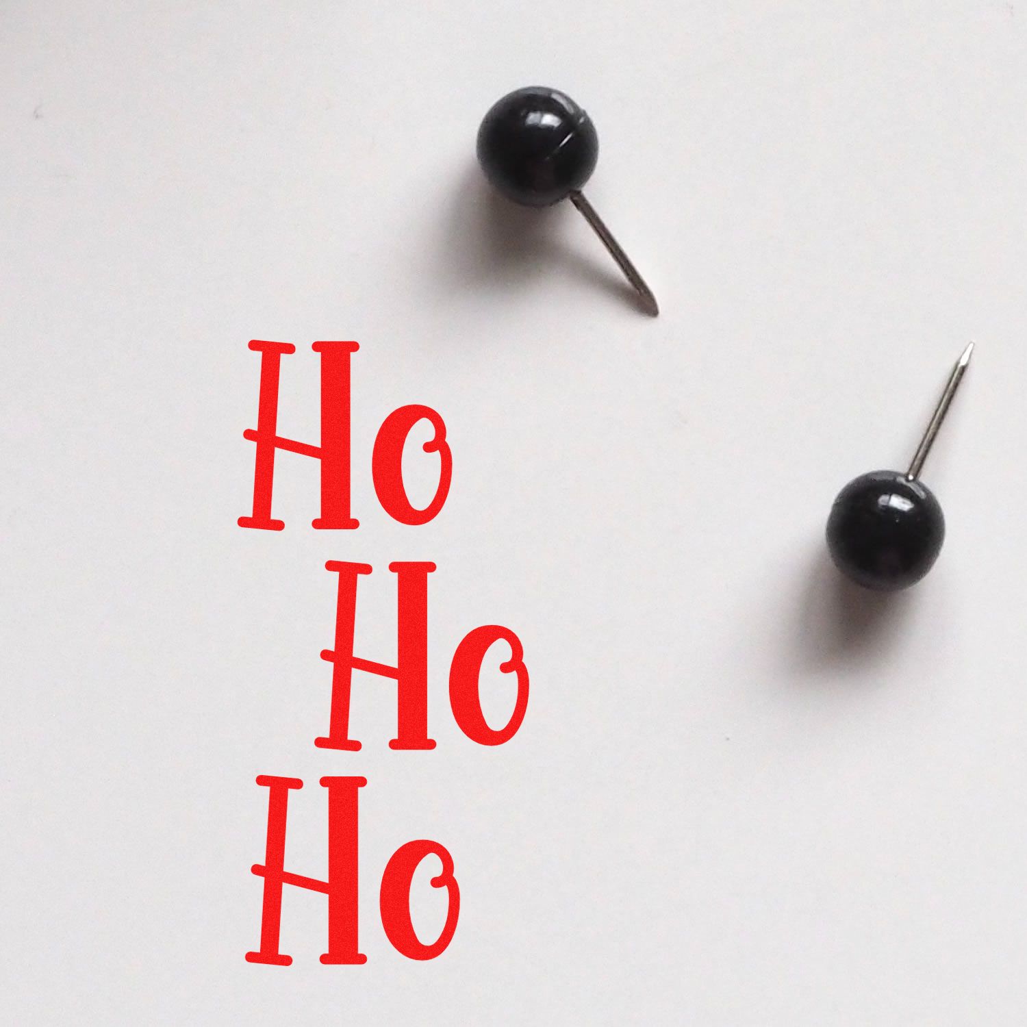 Ho Ho Ho Christmas rubber stamp design in red, shown with pushpins on white paper for holiday card making and crafts.