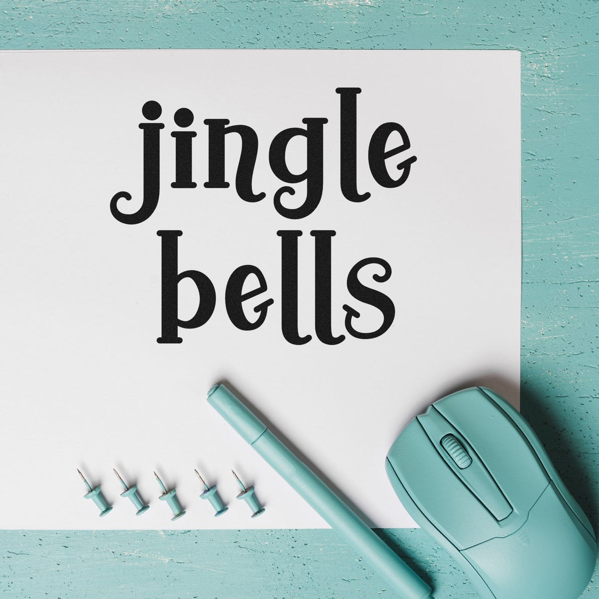 Jingle Bells PSI Pre-Inked Stamp imprint stamped in black ink. Two large rows of decorative serif lettering read “Jingle Bells.”