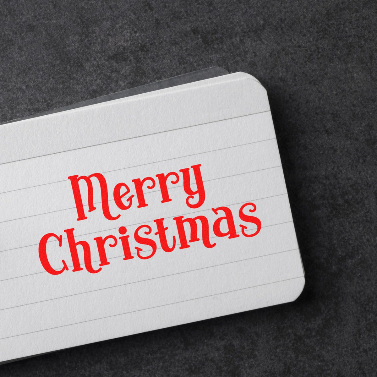 Red Merry Christmas rubber stamp on a note card, ideal for holiday cards, festive stationery, and paper crafting.