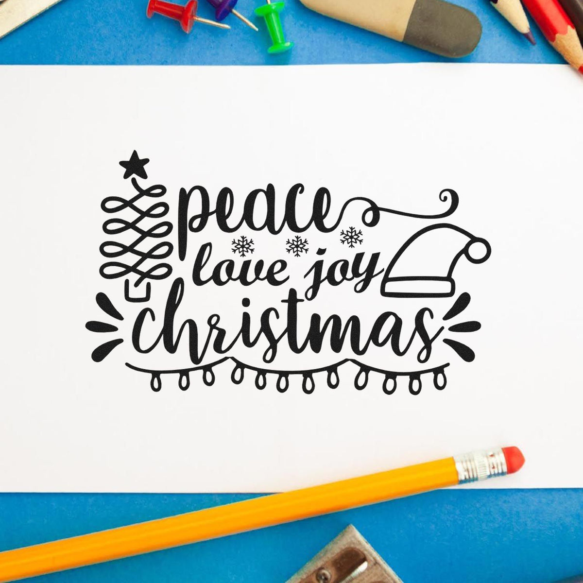 Christmas rubber stamp design with peace, love and joy lettering, Santa hat, and holiday lights for festive cardmaking.
