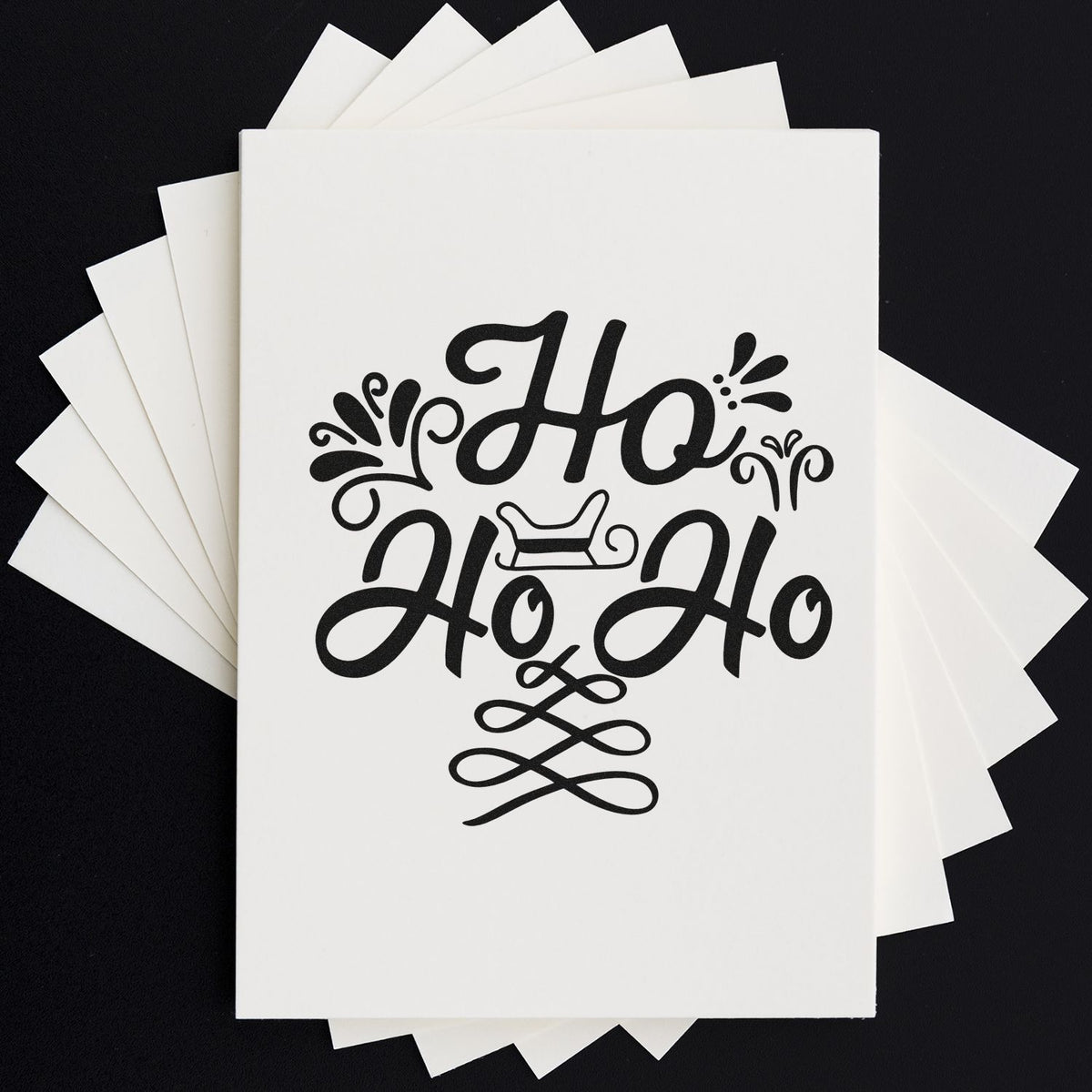 Decorative Ho Ho Ho rubber stamp design for Christmas cards, featuring festive script and flourish accents on stacked paper.