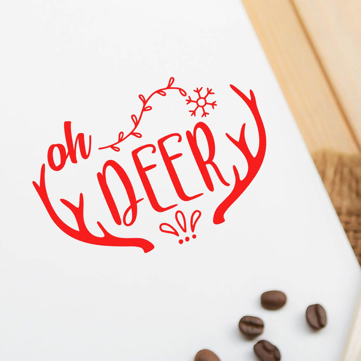 Custom Christmas rubber stamp design with red Oh Deery deer antlers graphic on white paper, with coffee beans.