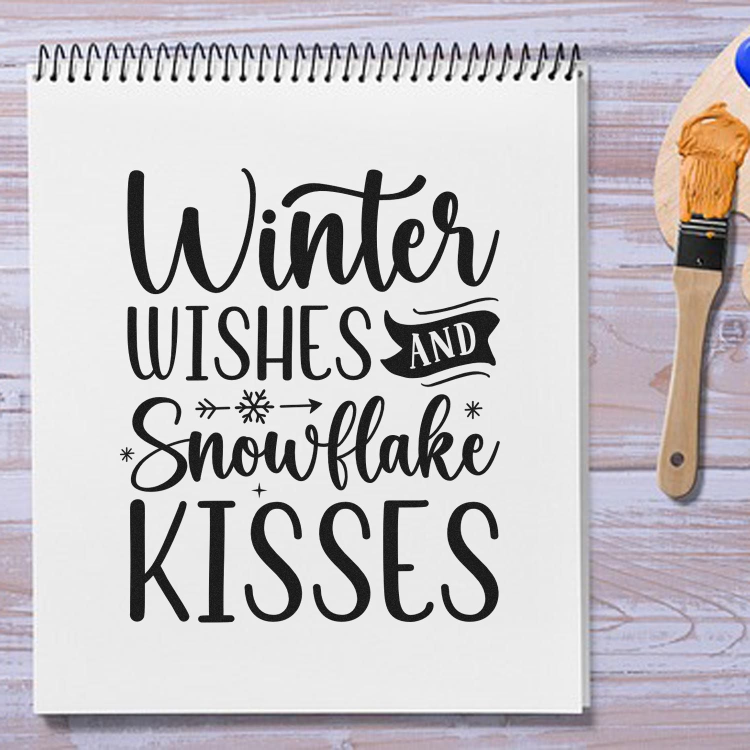 Winter Wishes and Snowflake Kisses rubber stamp design on notebook, with stamp brush for seasonal crafting.