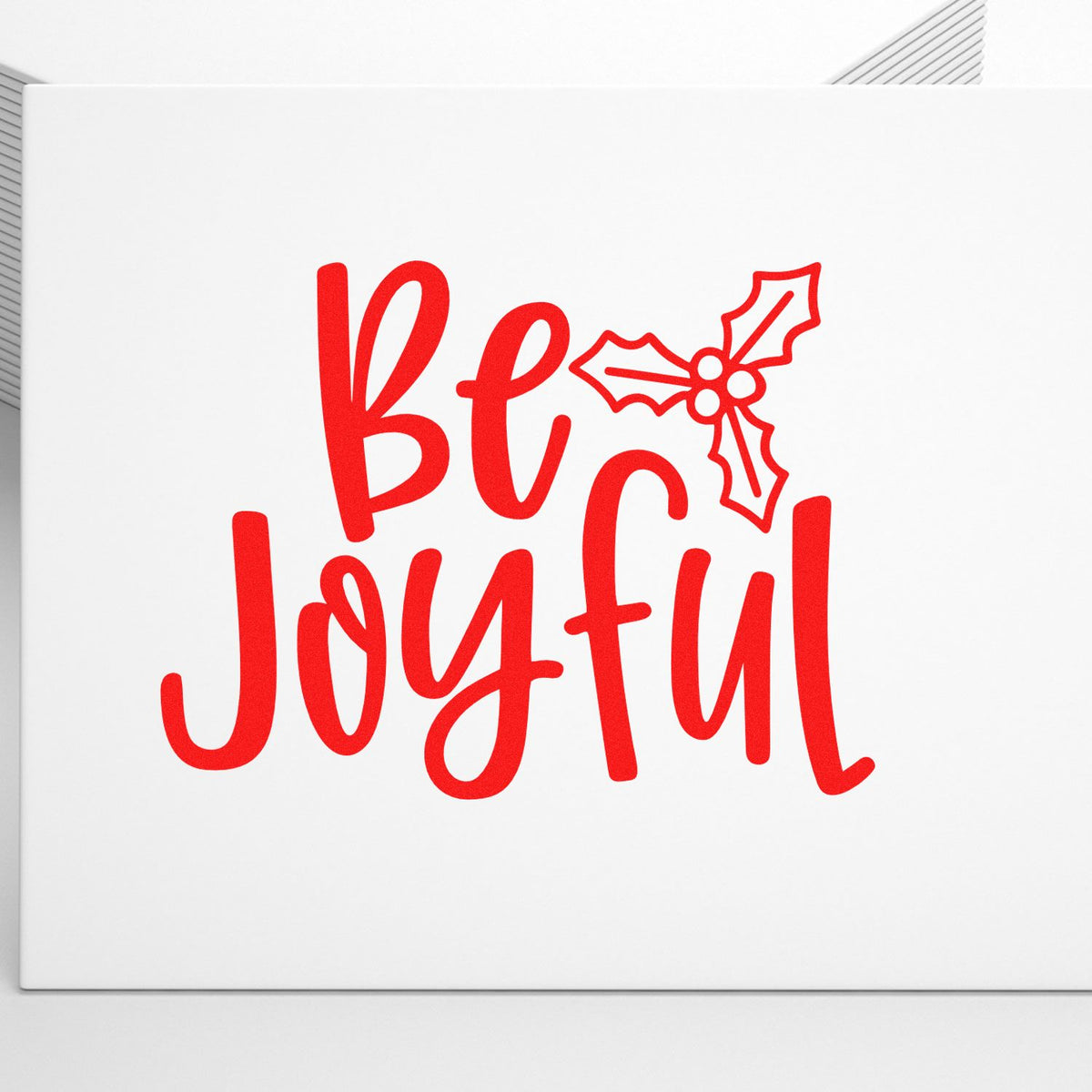 Be Joyful Christmas rubber stamp design with festive holly in red script for holiday cards and crafting.