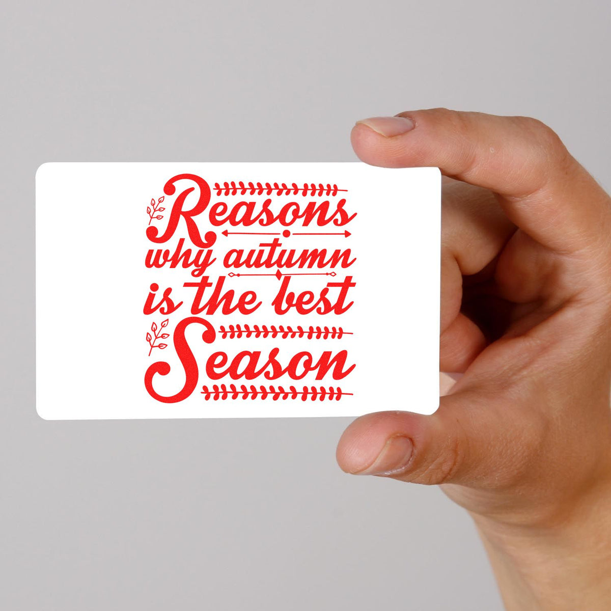 Autumn rubber stamp design reading Reasons why autumn is the best season on a card held by hand.