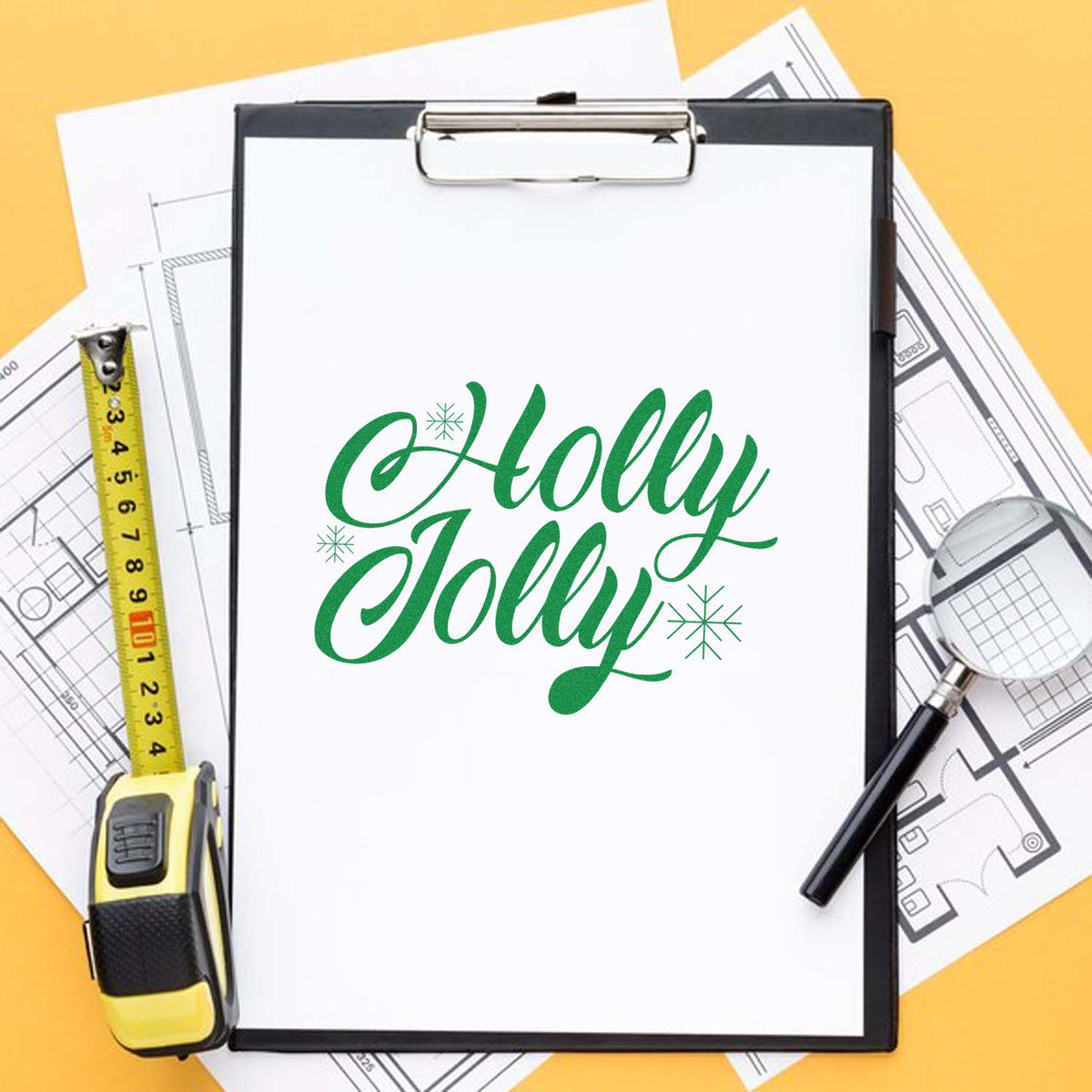 Holly Jolly holiday rubber stamp design mockup on clipboard with measuring tape and blueprint background.