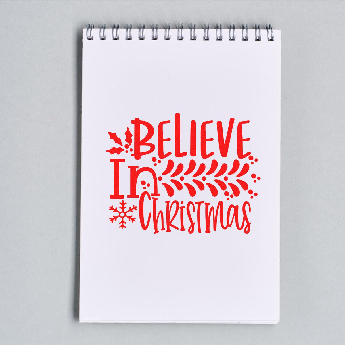 Christmas rubber stamp design reading Believe in Christmas with holly and snowflake accents, ideal for festive cards and crafts.