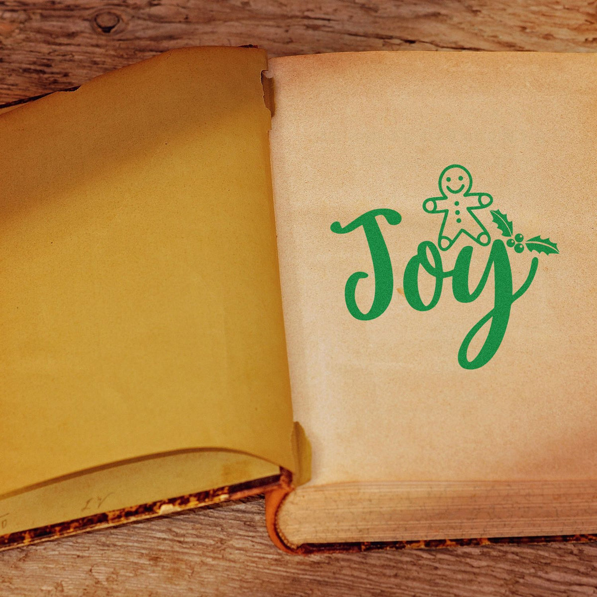 Christmas Joy rubber stamp with gingerbread man and holly on an open vintage book page.
