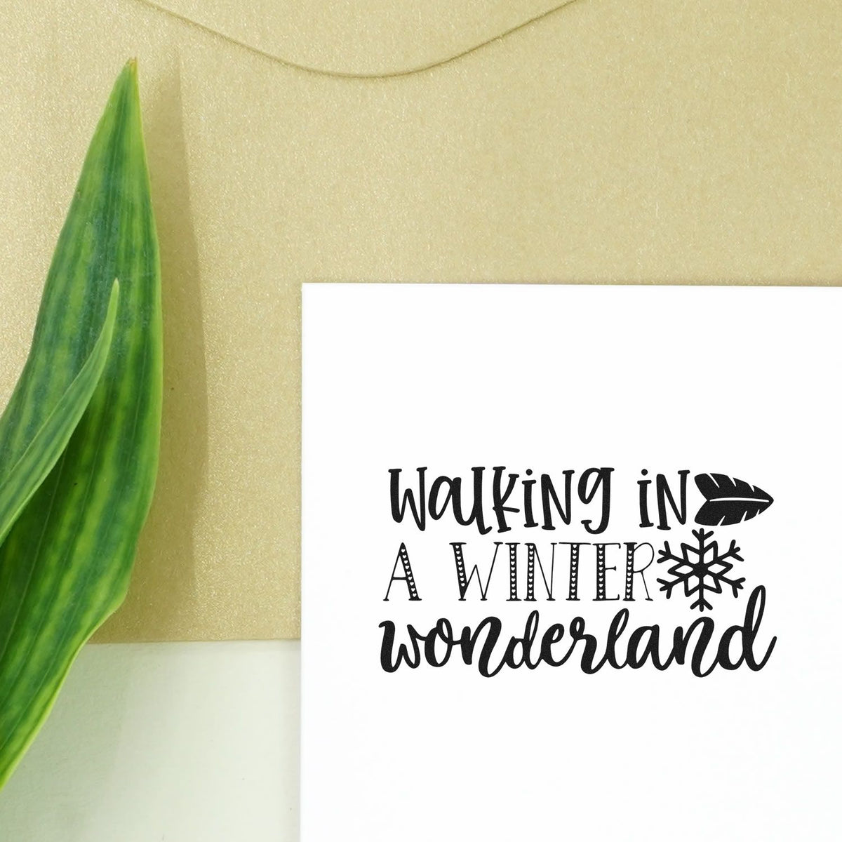 Walking In Winter Wonderland Pre-Inked Stamp – Slim imprint stamped in black ink. The words "Walking in a winter wonderland" appear with a snowflake and evergreen sprig.