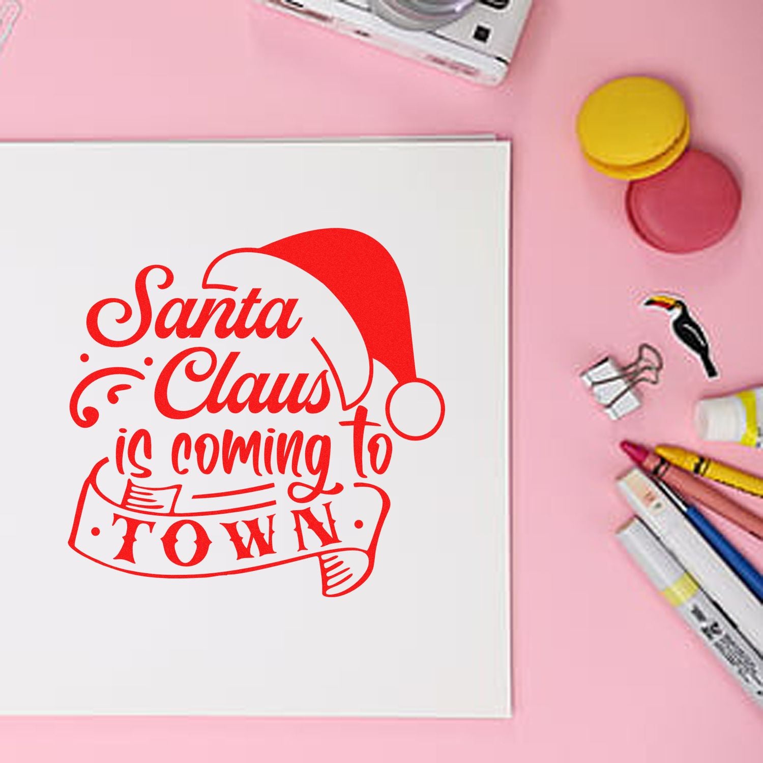 Christmas rubber stamp design reading Santa Claus is coming to town on a greeting card with craft supplies.
