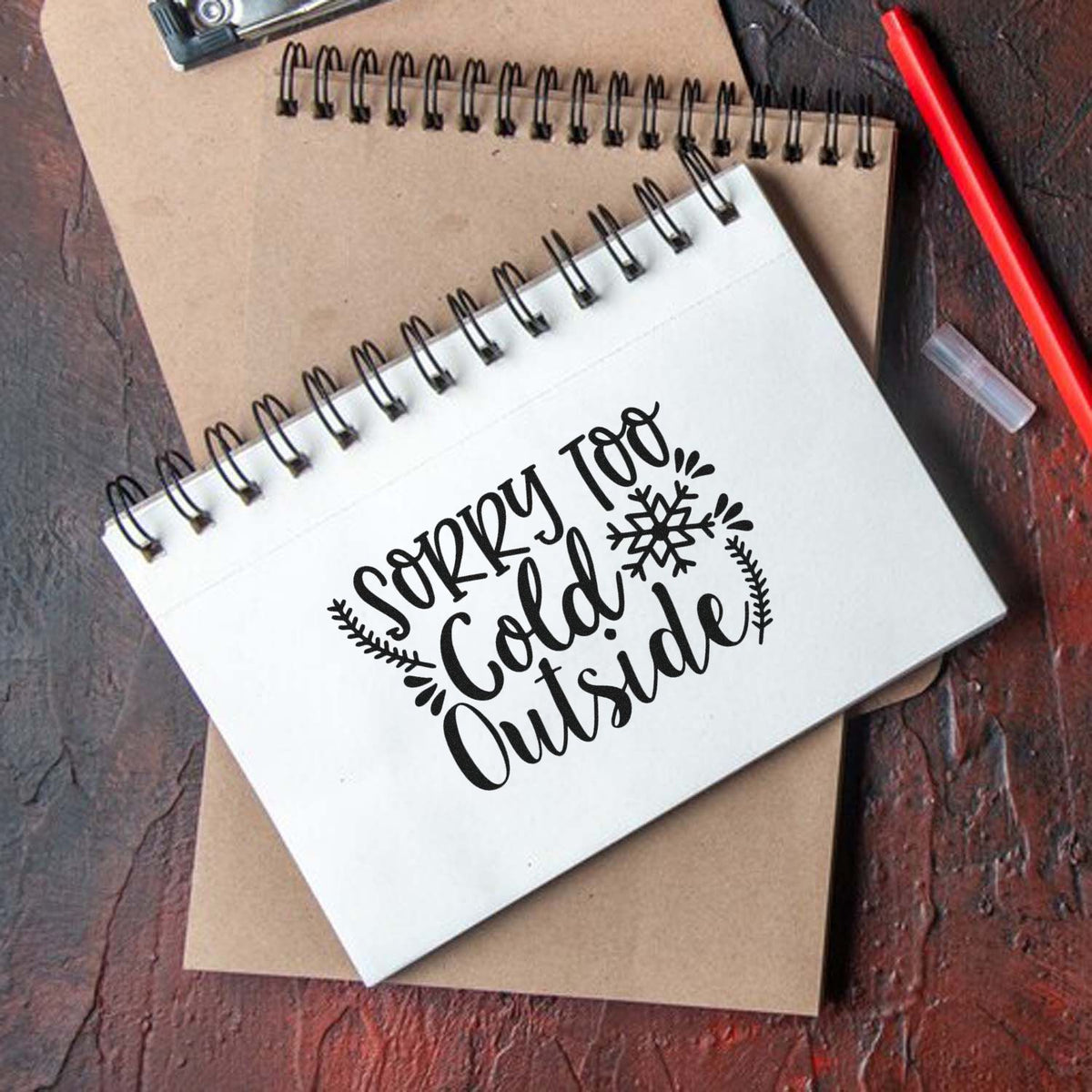 Winter rubber stamp design reading Sorry Too Cold Outside on a notebook, ideal for custom crafts and stationery.