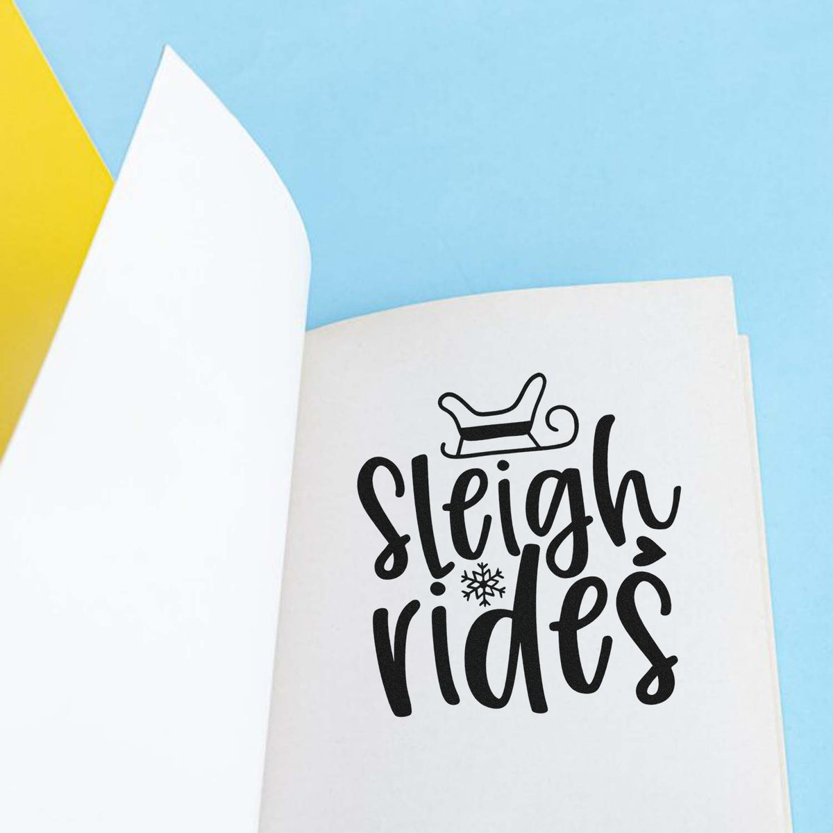 Sleigh Rides With Snowflake Slim Pre-Inked Stamp imprint stamped in black ink. The words "Sleigh rides" appear beneath a sleigh with a snowflake accent.