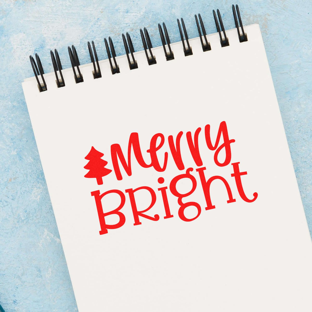 Merry Bright holiday rubber stamp design in red on a spiral notepad for Christmas crafting and card making