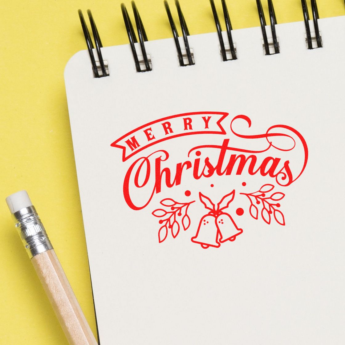 Merry Christmas rubber stamp design on notebook, with pencil, for holiday card making and festive craft projects.