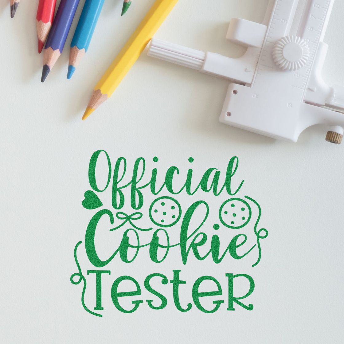 Custom rubber stamp design for bakers reading Official Cookie Tester with pencils and stamping tool on white.