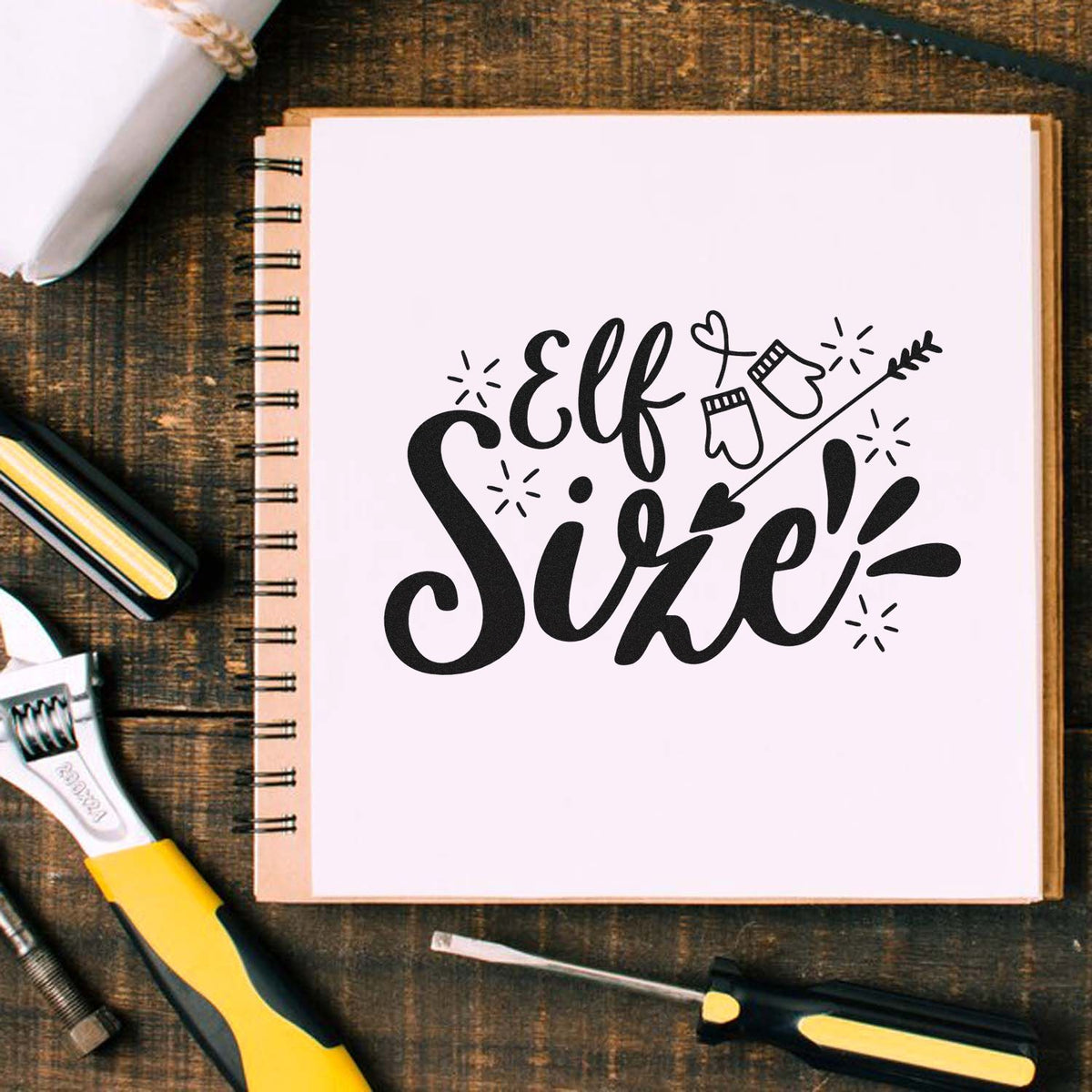 Elf Sire rubber stamp design displayed in a craft notebook with tools, perfect for holiday card making.