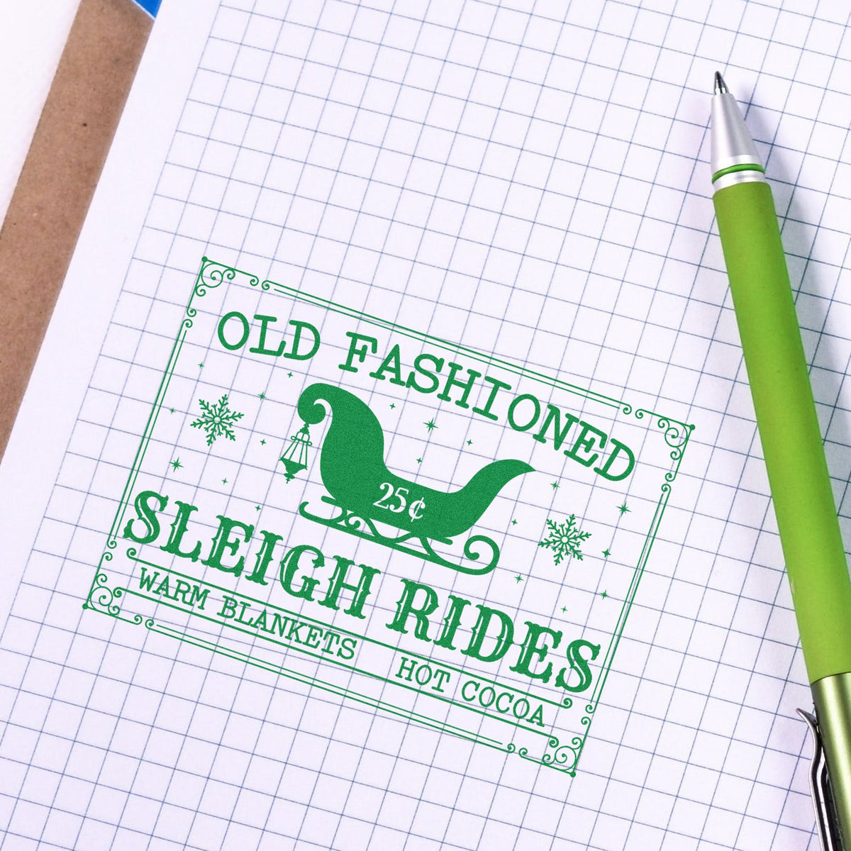 Green old-fashioned sleigh rides rubber stamp design with warm blankets and hot cocoa text on graph paper.