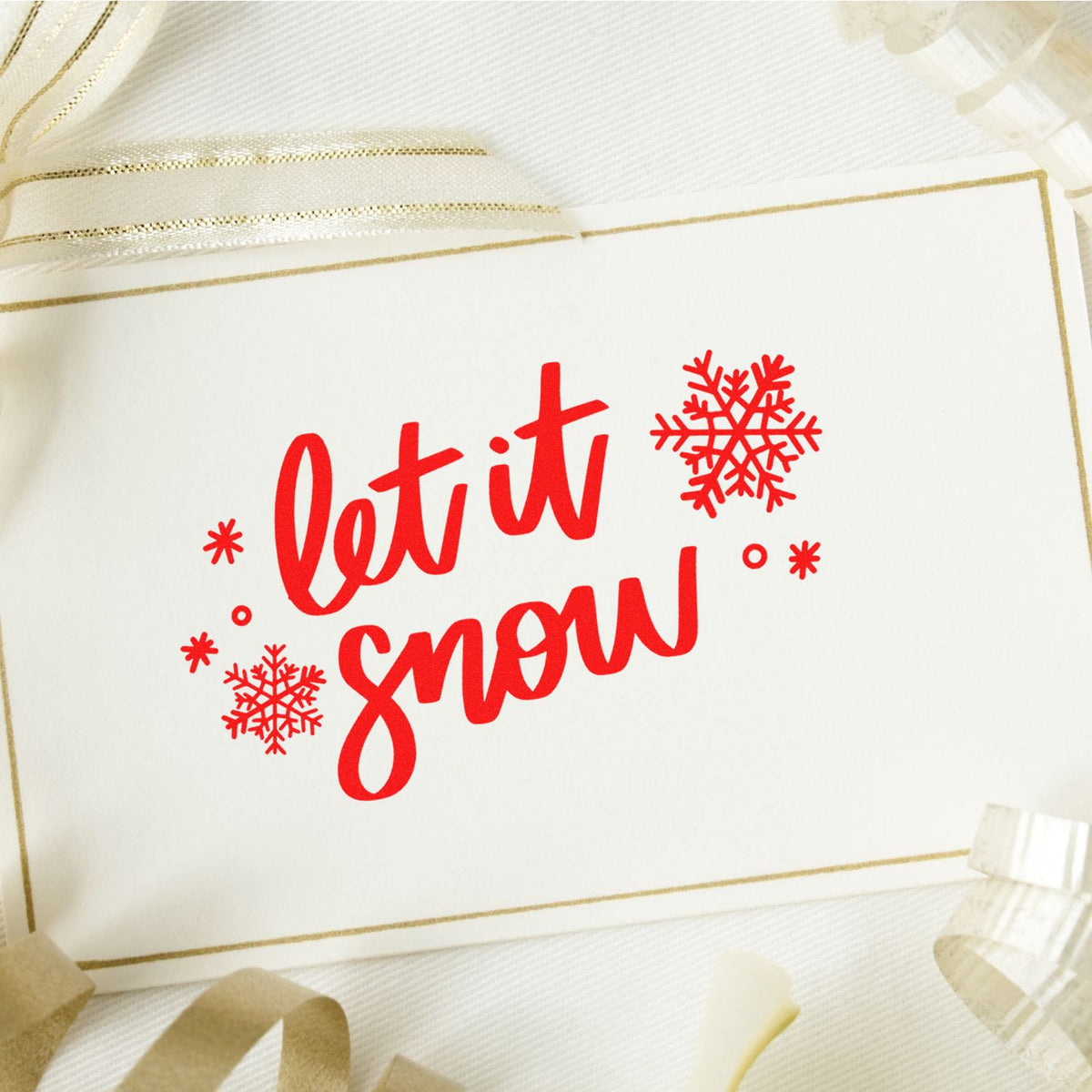 Red Let It Snow Christmas rubber stamp on white holiday card with snowflakes and gold ribbon border.