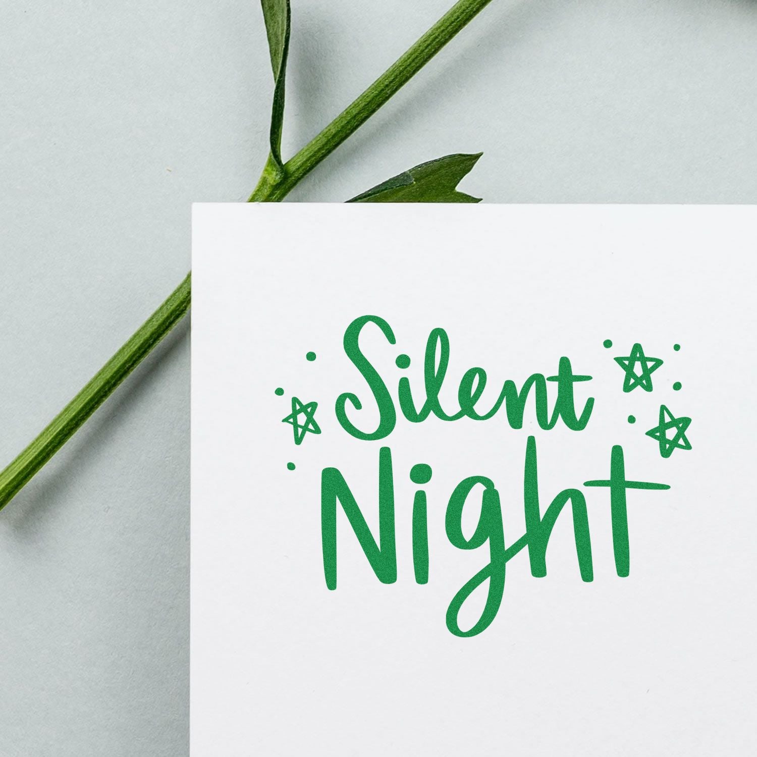 Silent Night Christmas rubber stamp design in green on white card with star accents and greenery background.