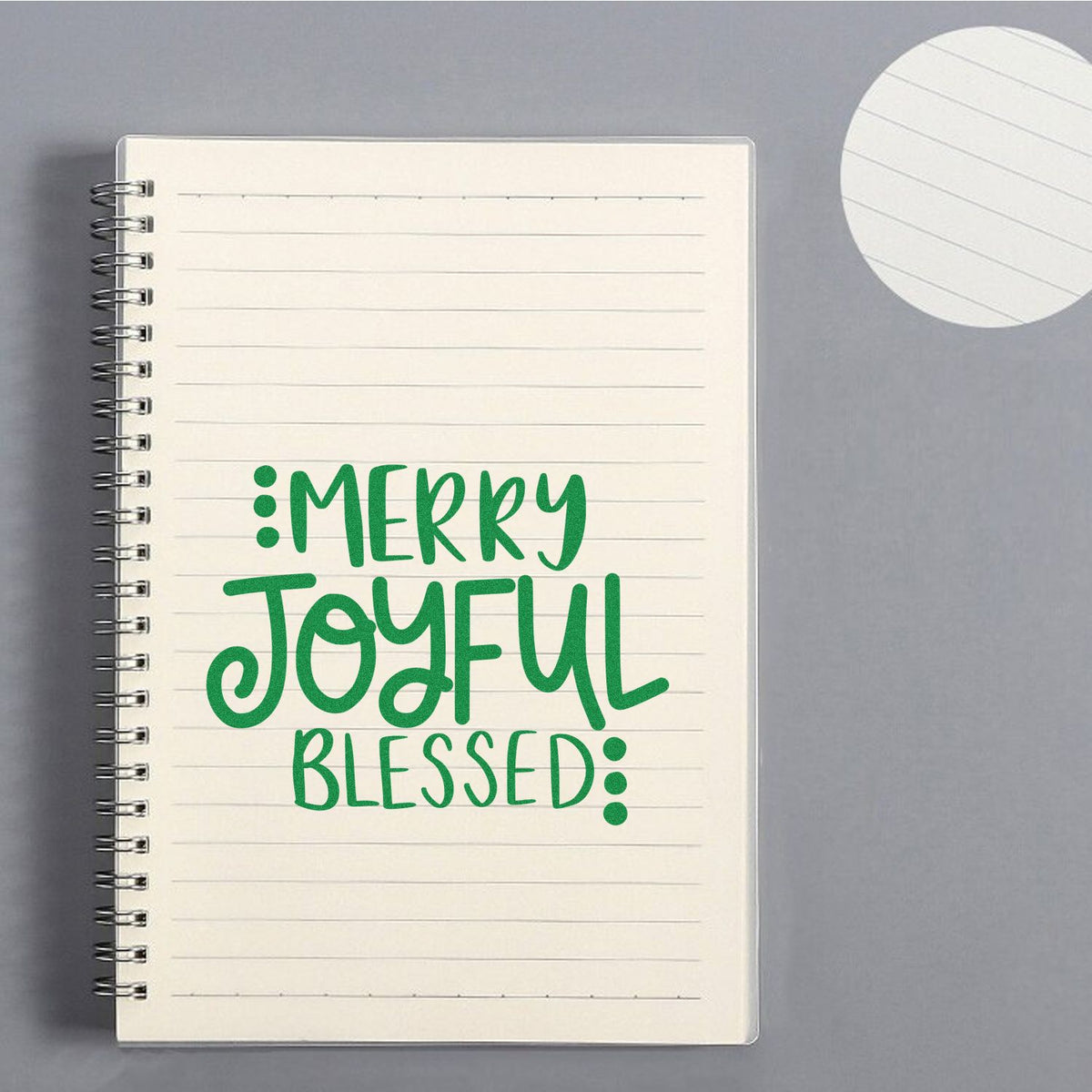 Christmas rubber stamp sample with Merry Joyful Blessed in green on a lined notebook page.