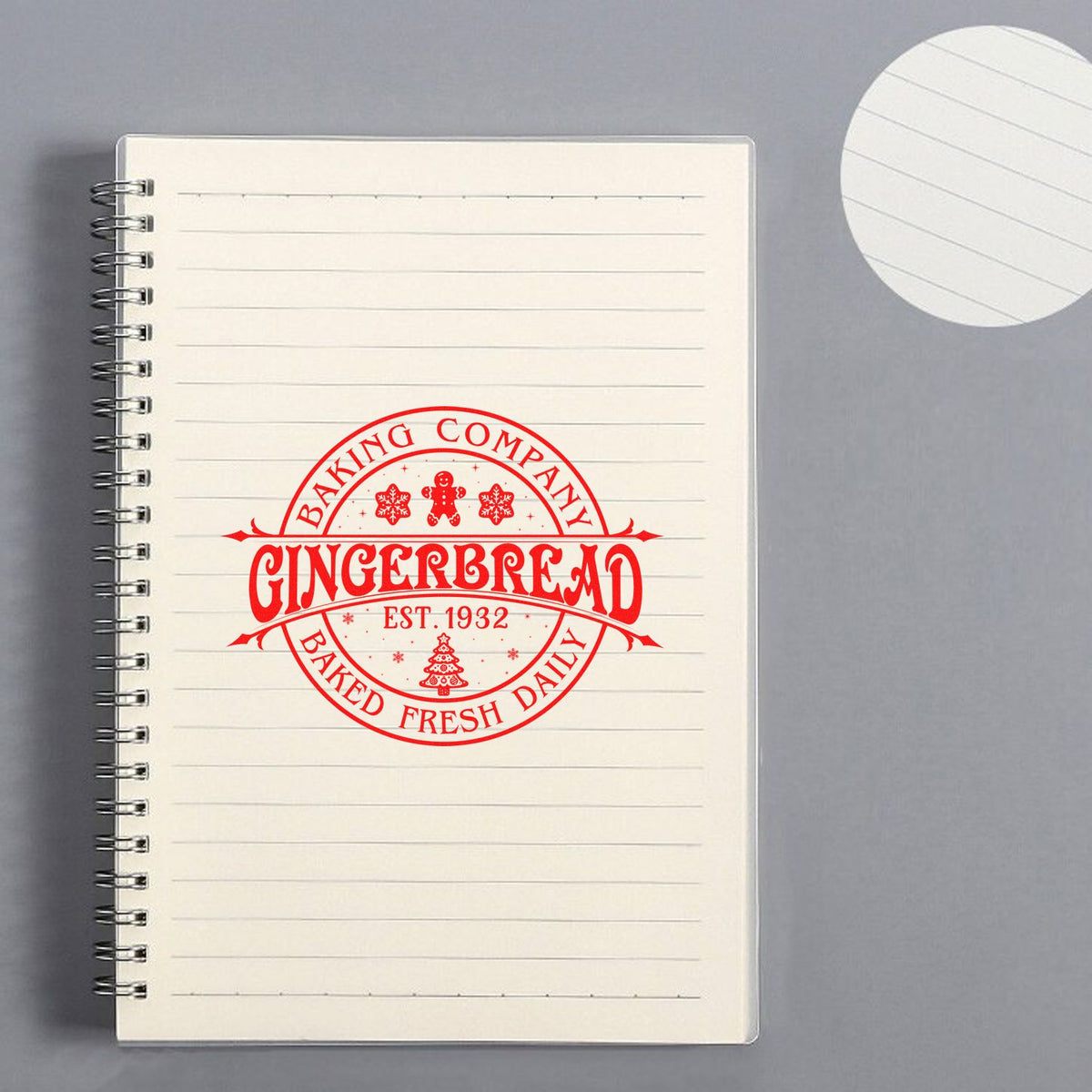 Custom bakery rubber stamp mockup with Gingerbread Baking Company logo, Baked Fresh Daily, on lined notebook.