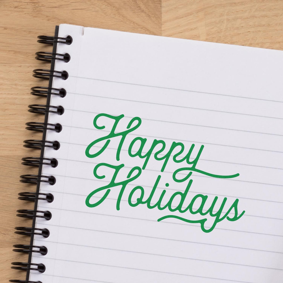 Happy Holidays rubber stamp in green script on a notebook page for festive card making and holiday crafting.