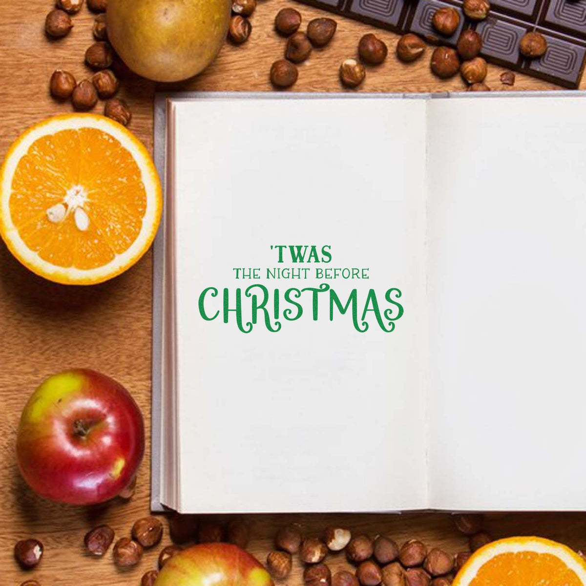 Christmas rubber stamp design on open notebook, reading Twas the Night Before Christmas, with festive fruit and coffee beans.