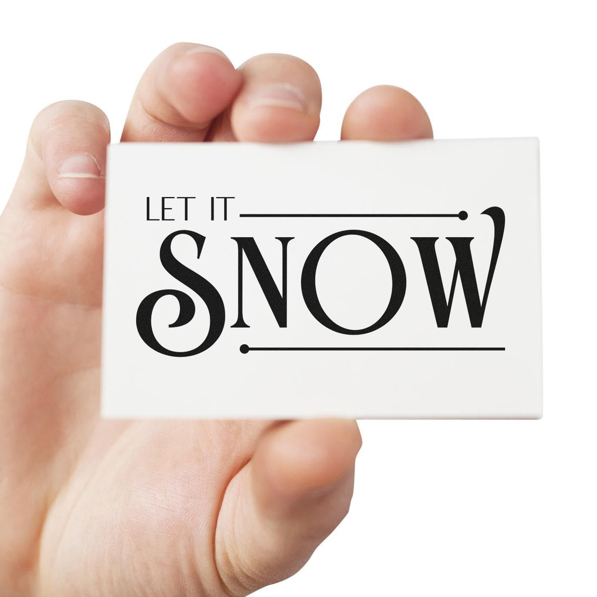 Hand holding Let It Snow rubber stamp for winter crafts, holiday cards, and festive packaging.