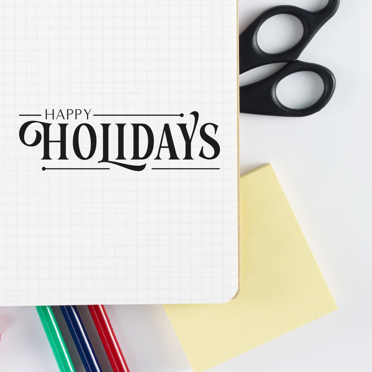 Happy Holidays rubber stamp on notebook with craft supplies for festive card making and holiday projects