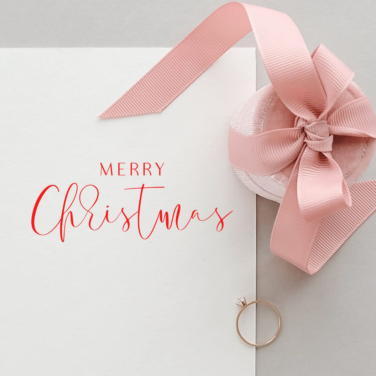 Merry Christmas rubber stamp design on white gift packaging with pink ribbon bow, ideal for festive holiday wrapping.