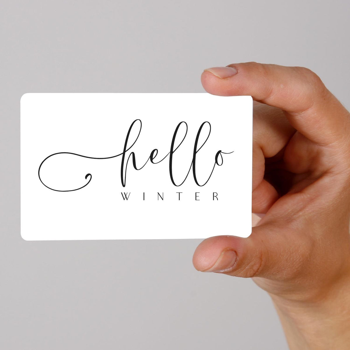Hand holding a Hello Winter script rubber stamp design for seasonal greeting cards.
