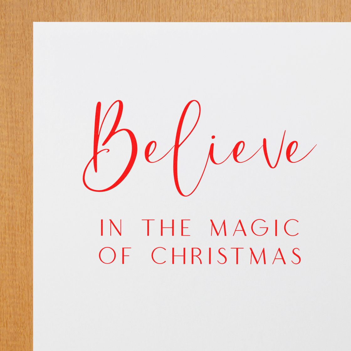 Red Christmas rubber stamp design with Believe in the Magic of Christmas script on white paper.