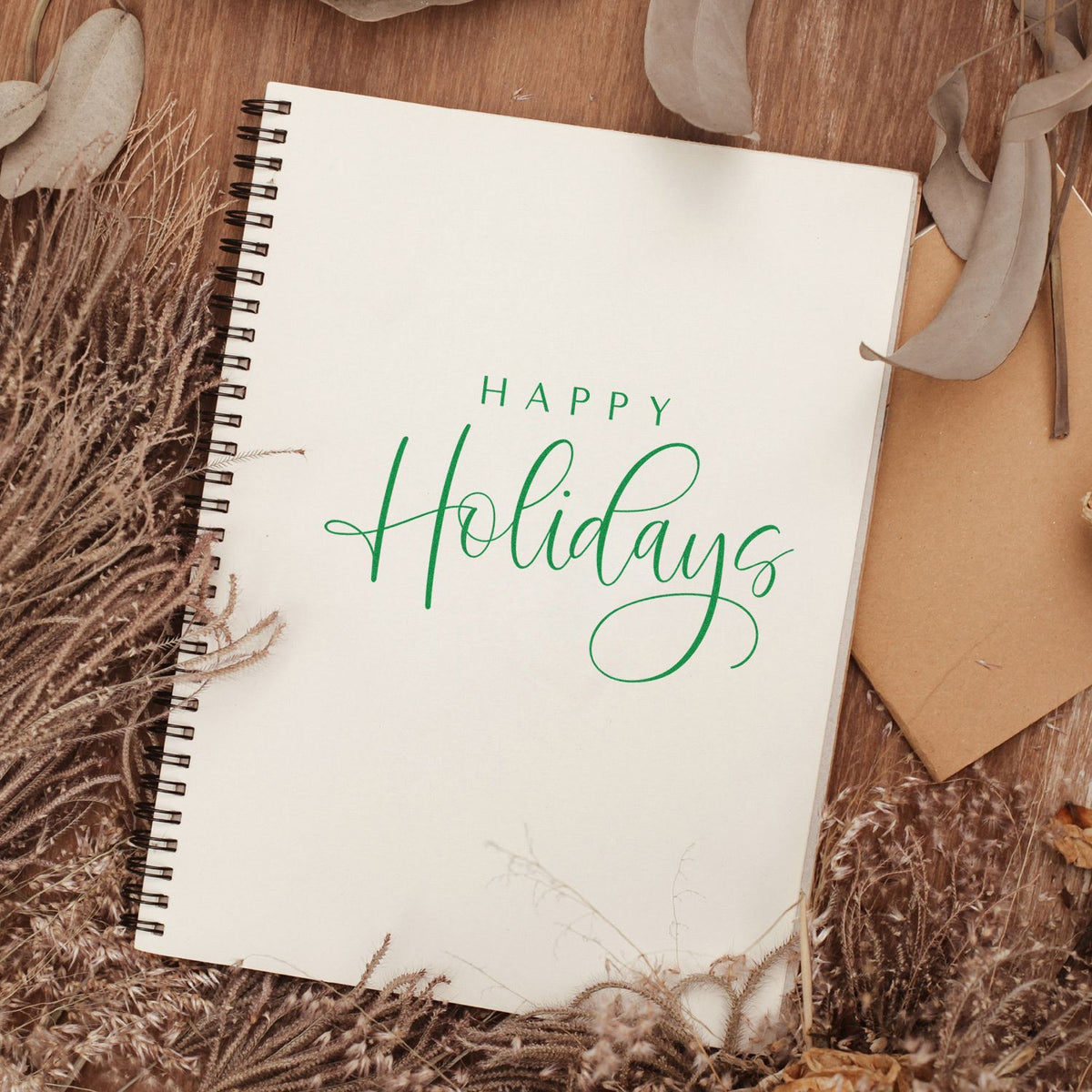 Green Happy Holidays rubber stamp impression on a spiral notebook, ideal for festive cards and handmade stationery.
