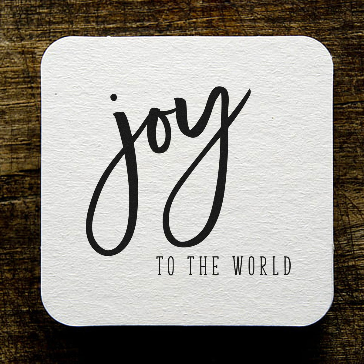 Joy to the World rubber stamp design with elegant black script on textured white background for holiday crafting.