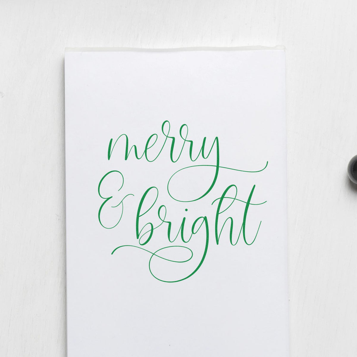 Green Merry & Bright calligraphy rubber stamp on white card for holiday cards, gift wrap, and festive packaging.