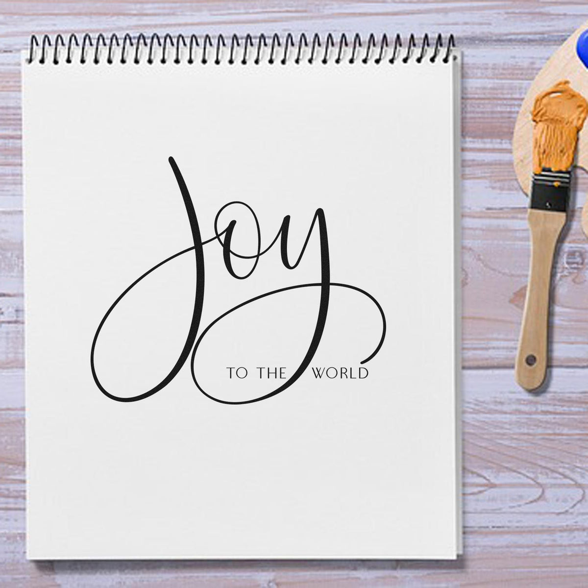 Joy to the World calligraphy rubber stamp design on sketchbook, perfect for holiday card making and craft projects.