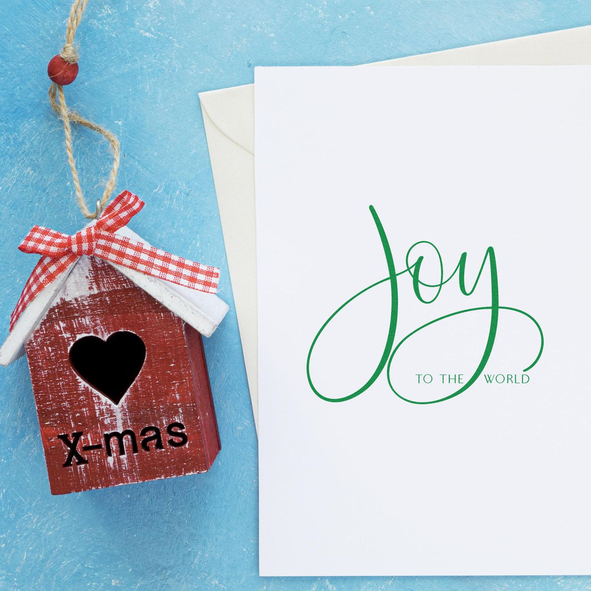 Christmas rubber stamp design with handmade birdhouse ornament and Joy to the World greeting card on blue background.