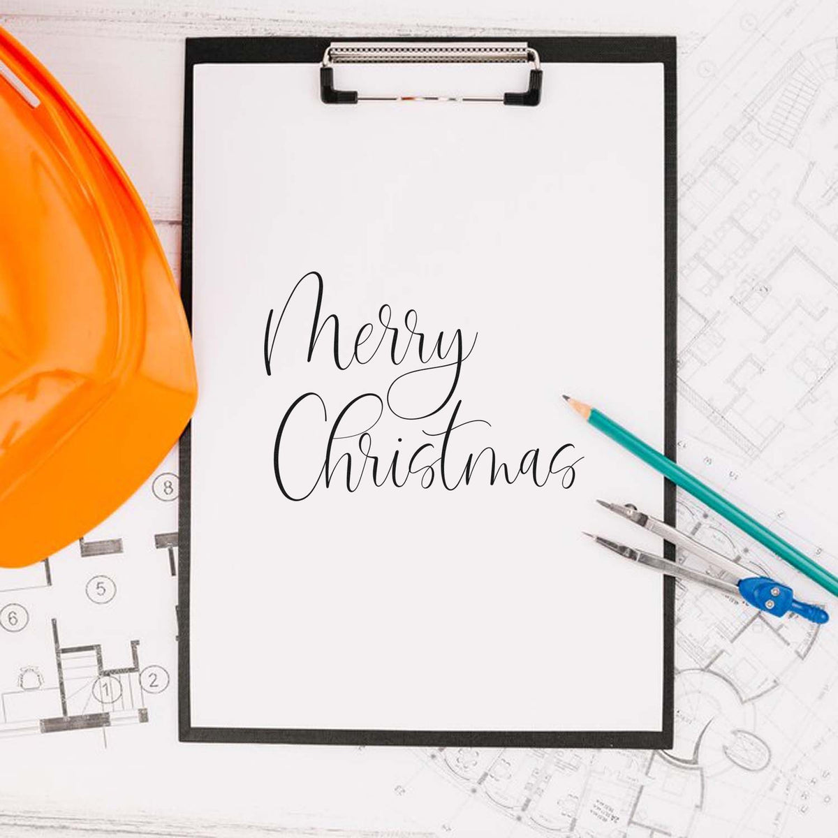 Merry Christmas construction rubber stamp design on clipboard with blueprint, hard hat, and drafting tools.