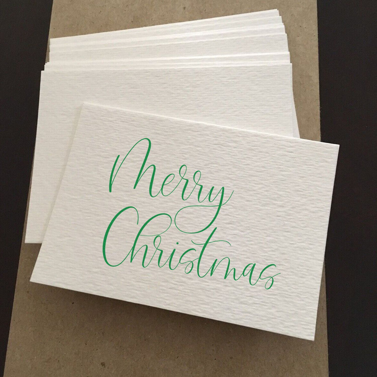 Custom Merry Christmas rubber stamp on white cocktail napkins for holiday parties, gift wrapping, and festive packaging.