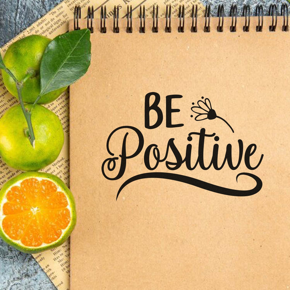 Be Positive rubber stamp design on kraft notebook with citrus slices and leaves for uplifting journaling crafts.