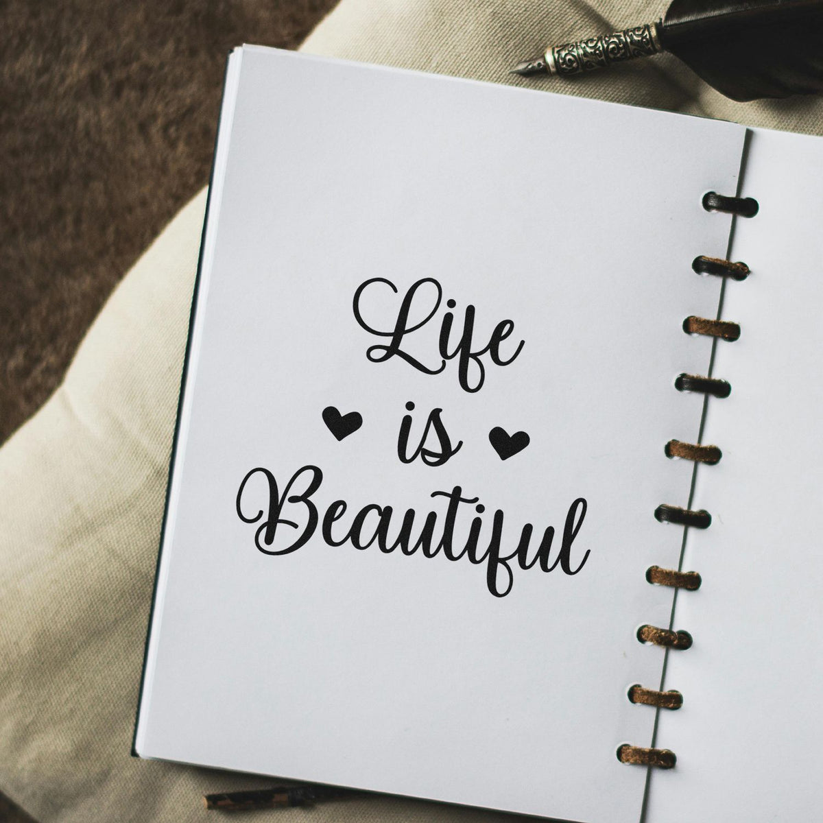 Motivational quote rubber stamp reading Life is Beautiful on a spiral journal page for handmade stationery.