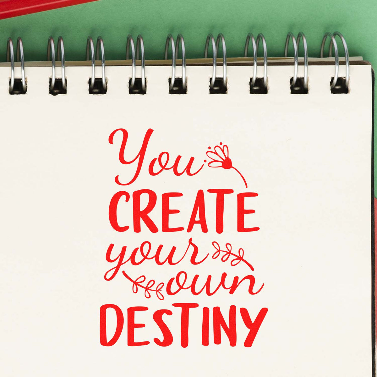 Motivational rubber stamp design with quote You create your own destiny in red on a spiral notebook page.