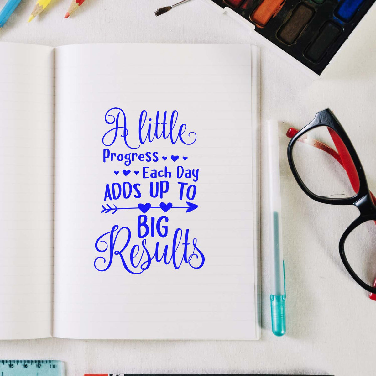 Motivational rubber stamp impression on notebook: A little progress each day adds up to big results for planners and journaling.