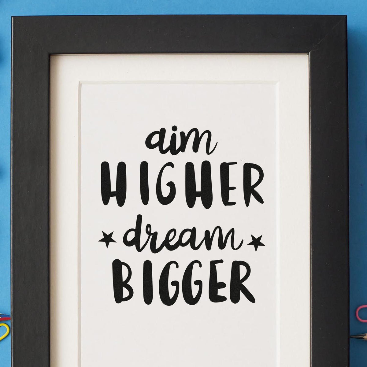 Custom rubber stamp design with inspirational quote Aim Higher, Dream Bigger in bold hand-lettered typography.