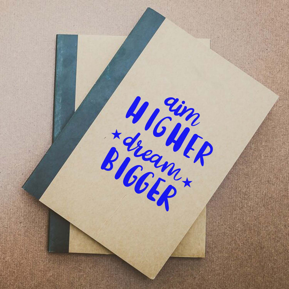 Custom rubber stamp on notebook cover with motivational quote Aim Higher, Dream Bigger for planners, journals, and gifts.