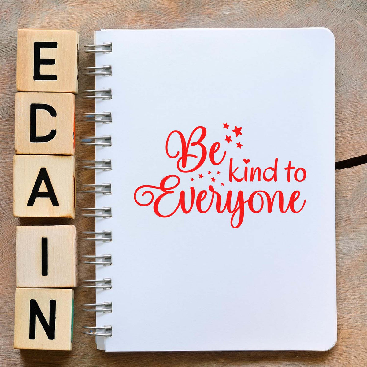 Wooden alphabet rubber stamp blocks beside notebook featuring Be kind to everyone for craft, journaling, and DIY stamping.